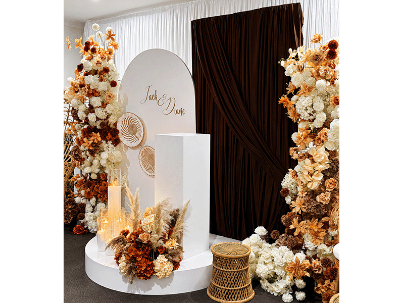 Jack and Diane boho wedding centrepiece on white plinth with autumn floral arch and round backdrop