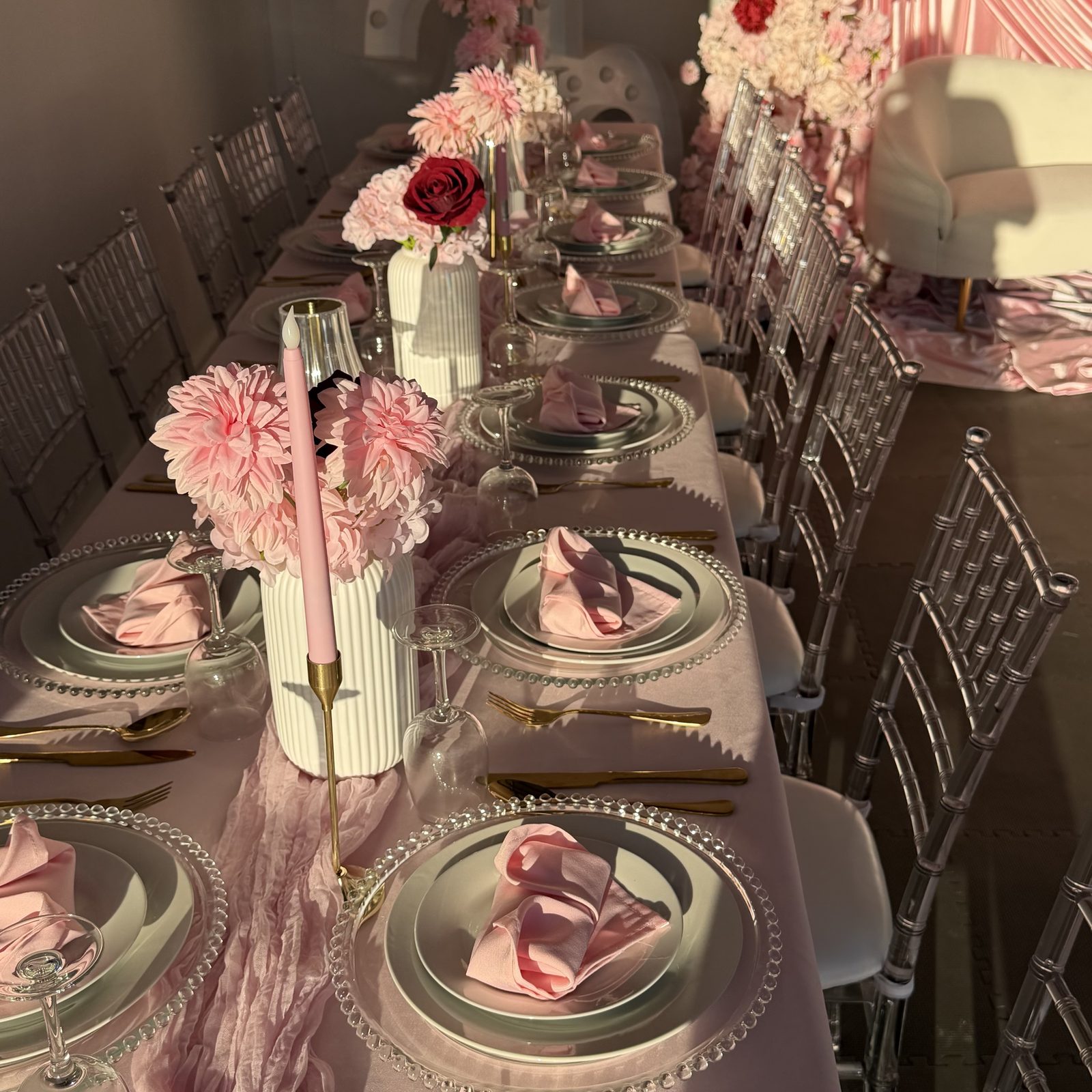 Pink table setting with beaded glass chargers, gold cutlery, taper candles and dahlia centrepieces