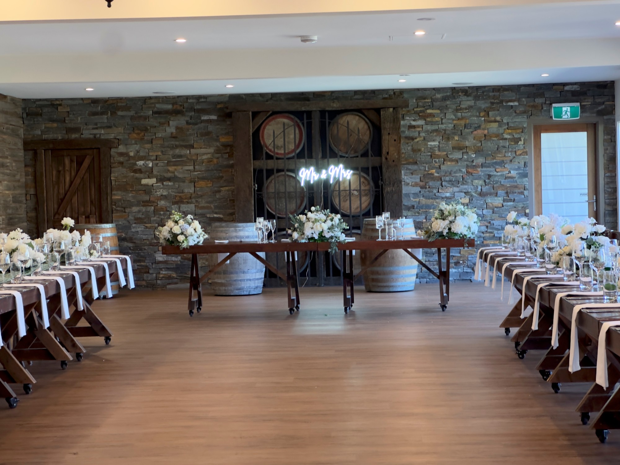 Winery wedding reception table setup with white florals and Mr and Mrs neon sign