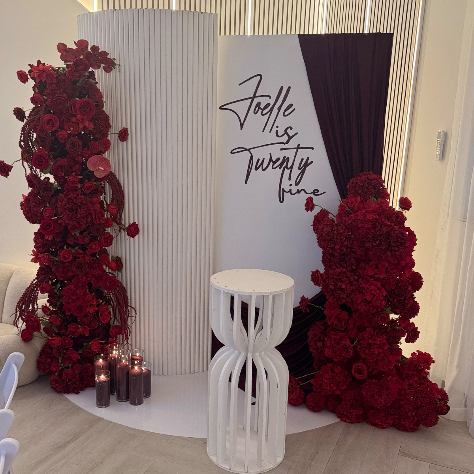 Red curved backdrop with pillar florals and vinyl decal hire Melbourne